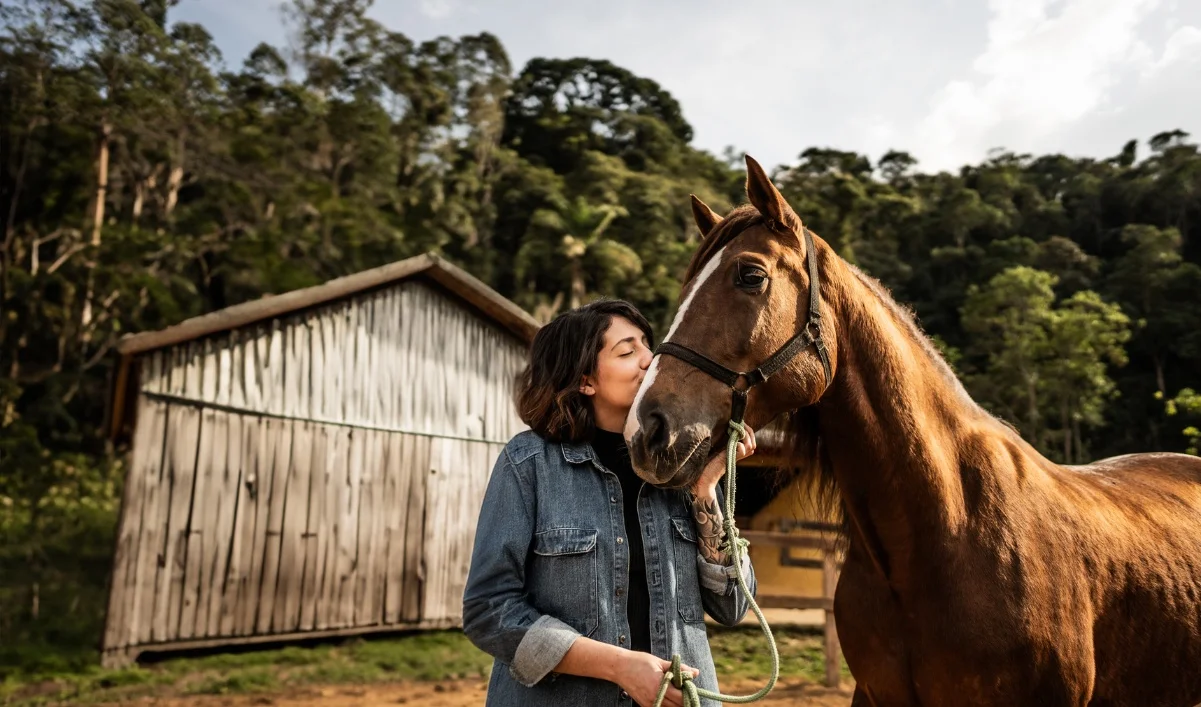 Women kissing her horse next to the barn on a farm